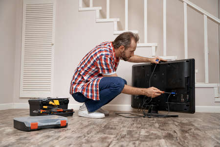 Young caucasian service man fixing tv setの写真素材