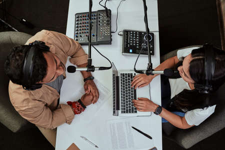 Top view of two radio hosts, young man and woman discussing various topics while moderating a live show in studioの写真素材