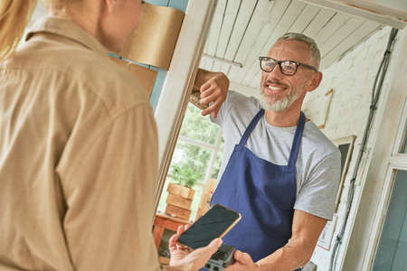 Woman customer paying using smartphone to caucasian manの写真素材