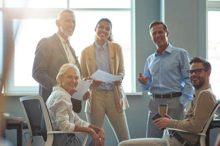 Strong and successful team. Group of happy multiracial business people smiling at camera while having a meeting at officeの写真素材