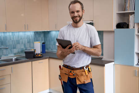 Young caucasian house master with tablet standing in kitchenの写真素材
