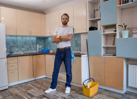 Young caucasian man standing with crossed hands in kitchen