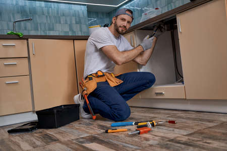 Young caucasian home master screwing part of kitchen furnitureの写真素材