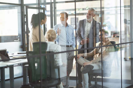 Group of multiracial colleagues discussing business and sharing fresh ideas while having a meeting in conference room, working together in the modern officeの写真素材