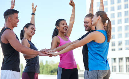 Happy young athletes holding right hands stackedの写真素材