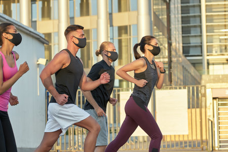 Young mixed race team in protective masks training outdoorsの写真素材