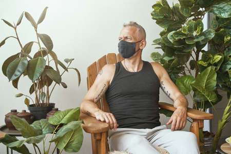 Self isolation. Middle aged caucasian man wearing protective face mask against coronavirus disease...