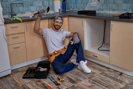 Happy young caucasian worker with raised hand holding hammerの写真素材