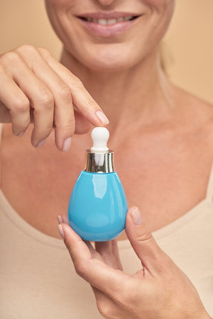 Vertical shot of a smiling woman showing a jar of cosmetic productの写真素材