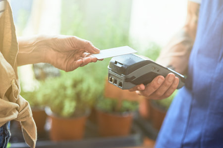 Woman paying contactless with card to male sellerの写真素材