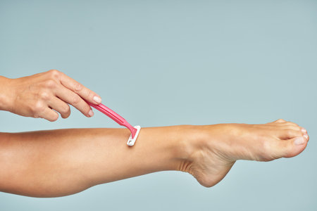 Woman deleting hair with help of pink razor by handの写真素材