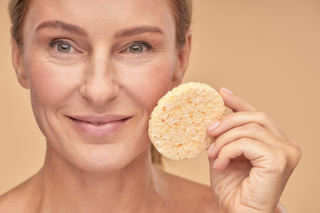 Pretty woman removing makeup with a spongeの写真素材