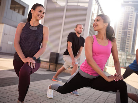 Smiling young girls doing lunges and talking to each otherの写真素材