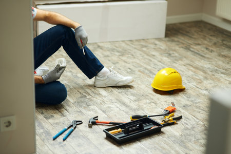Home repairs. Cropped shot of handyman holding screwdriver and wall plug socket. Home repair hand tools on laminate flooring. Home improvementの写真素材
