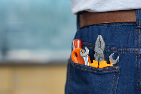 Close up shot of various plumbing hand tools in mans jeans back pocketの写真素材