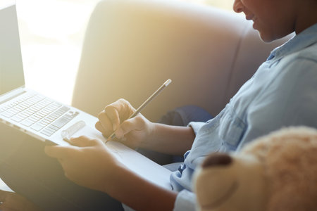 Cropped shot of happy teen schoolgirl drawing while doing homework, sitting on the sofa at homeの写真素材
