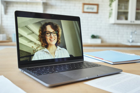 Close up of laptop screen with attractive female teacher smiling during video call, having online lesson with students studying from homeの写真素材