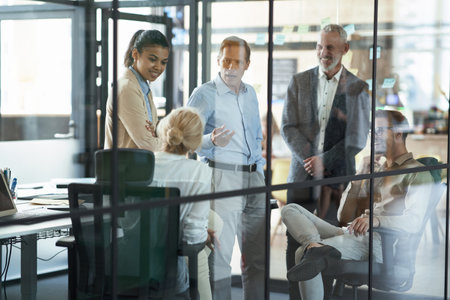 Group of multiracial coworkers discussing business and sharing fresh ideas while working together in the modern officeの写真素材