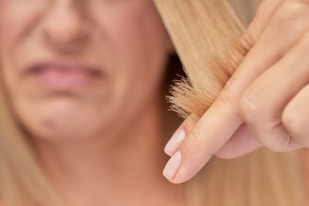 Split ends. Upset blonde woman looking at her damaged hair, selective focusの写真素材