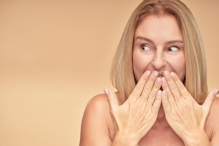 Surprised woman posing in studio on beige backgroundの写真素材