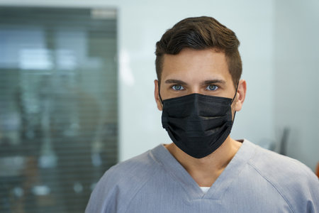 Young male doctor wearing mask and posing for cameraの写真素材