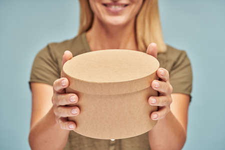 Happy attractive lady showing gift box in hands isolated on blue backgroundの写真素材