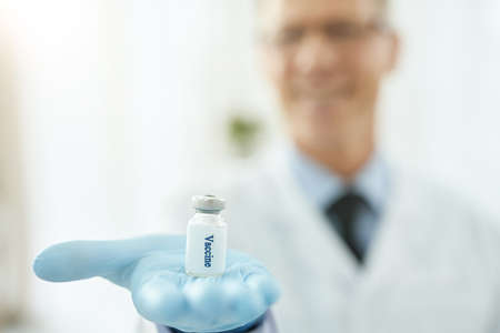 Doctor in sterile gloves holding bottle of vaccineの写真素材