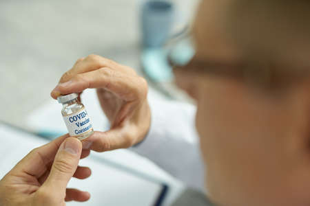 Male hands holding bottle of covid-19 vaccineの写真素材