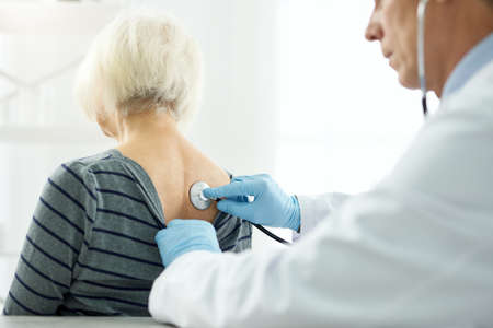 Doctor examining female patient with stethoscope in clinicの写真素材