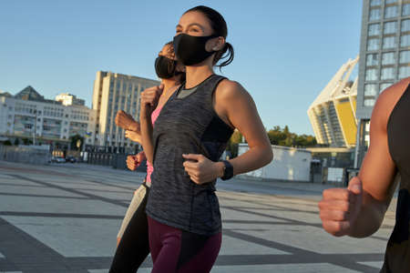 Young caucasian fit people in protective masks running