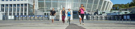 Young mixed racial team running to camera from stadiumの写真素材