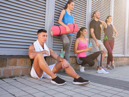 Young multiracial people resting near wall on streetの写真素材