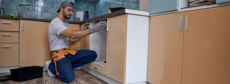 Young caucasian worker measuring drawer in kitchen furnitureの写真素材
