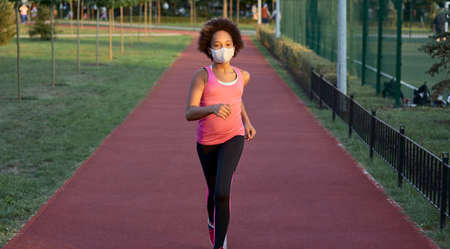 Sporty little girl in face mask running in parkの写真素材