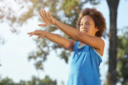 Cute Afro American girl doing exercise on the street