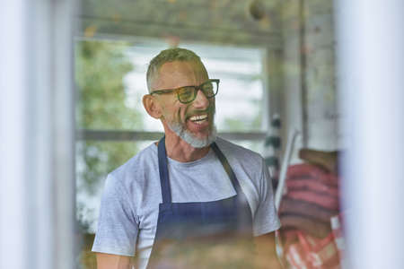 Happy middle aged caucasian man in apron smilingの写真素材