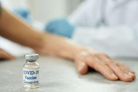Old woman hand resting on the table with COVID-19 vaccineの写真素材