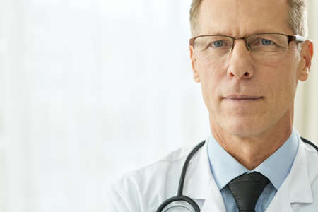 Good-looking male doctor standing against white backgroundの写真素材