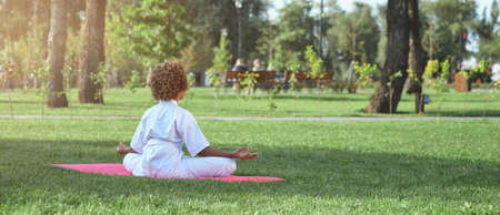 Little girl in karate kimono meditating in parkの写真素材