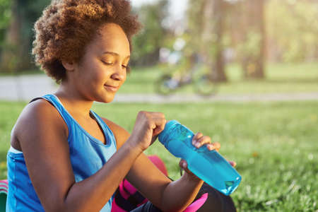 Adorable Afro American girl opening bottle of waterの写真素材