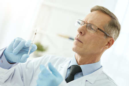 Serious male doctor holding syringe with vaccineの写真素材