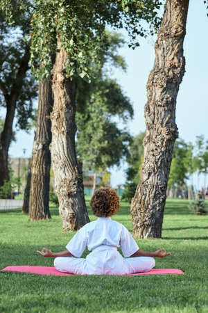 Afro American girl in karate kimono meditating outdoorsの写真素材