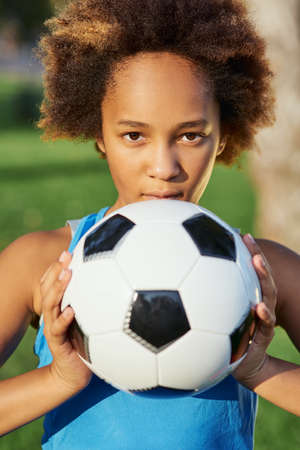Cute Afro American girl with soccer ball standing in the street