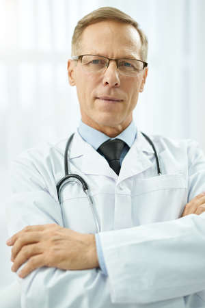 Handsome male doctor standing against white backgroundの写真素材