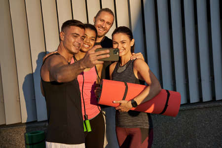 Happy four athletes making photo with smartphoneの写真素材