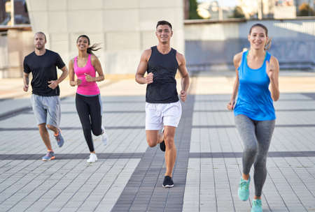 Smiling young runners jogging in the city togetherの写真素材