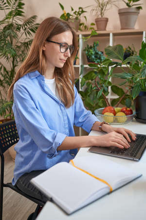 European beautiful female in glasses using laptop at homeの写真素材