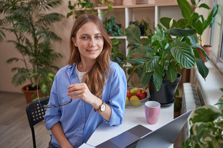 Smiling female student using laptop during classes onlineの写真素材
