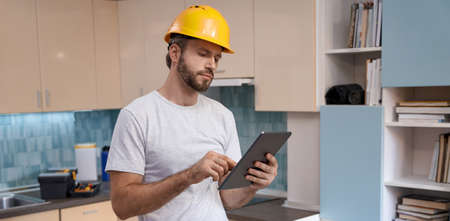 Builder in helmet working with tablet on kitchen backgroundの写真素材