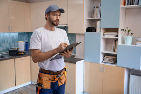 Young caucasian repairman writing in notebookの写真素材
